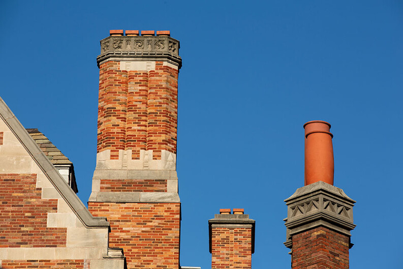 The roofline of Sterling Law Building with three brick chimneys of different sizes