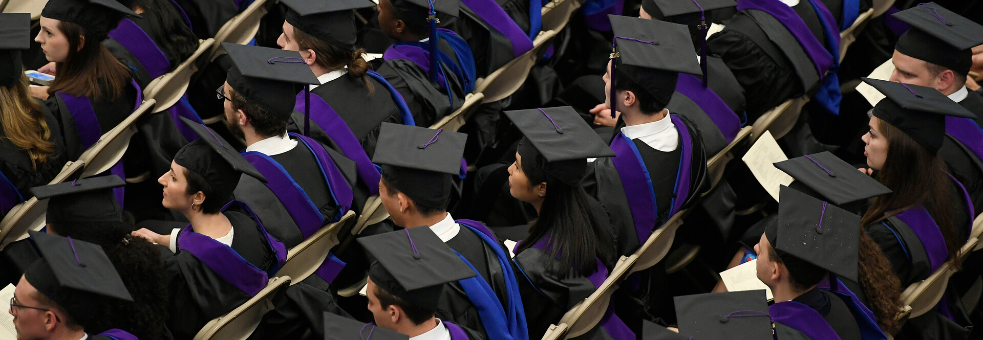 students seated in caps and gowns at Commencement