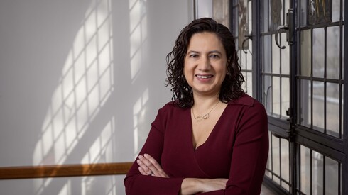 Anika Singh Lemar stands in front of a window with her arms crossed